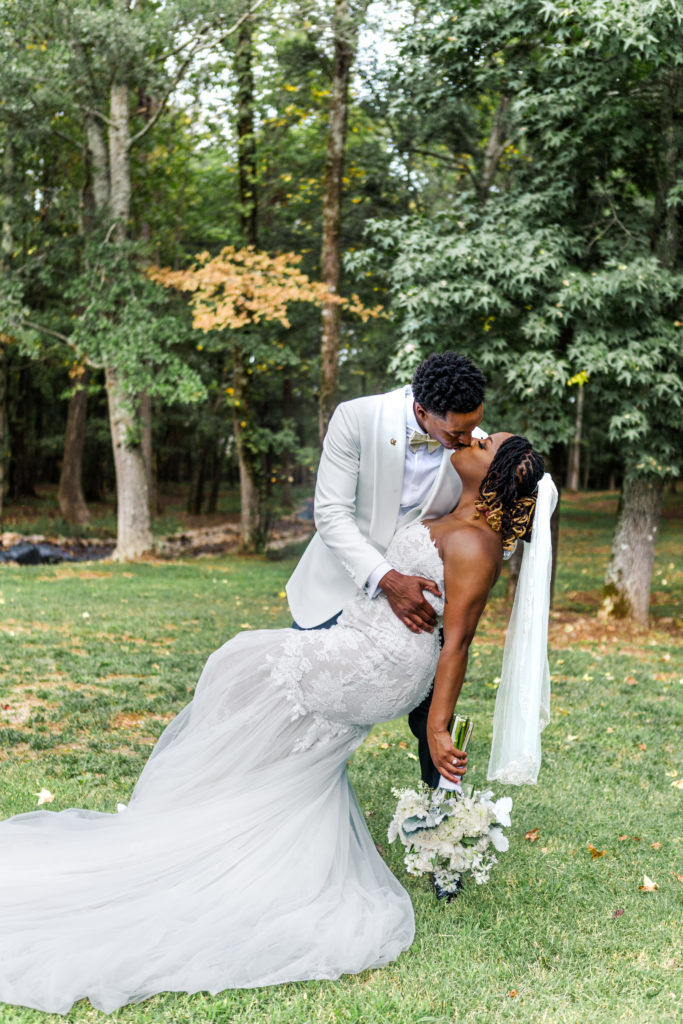 Groom dipping for a kiss with his Bride with bouquet created by Couture Creations of Huntsville Alabama
